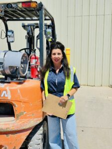 Christina, our OSHA safety officer standing near a forklift
